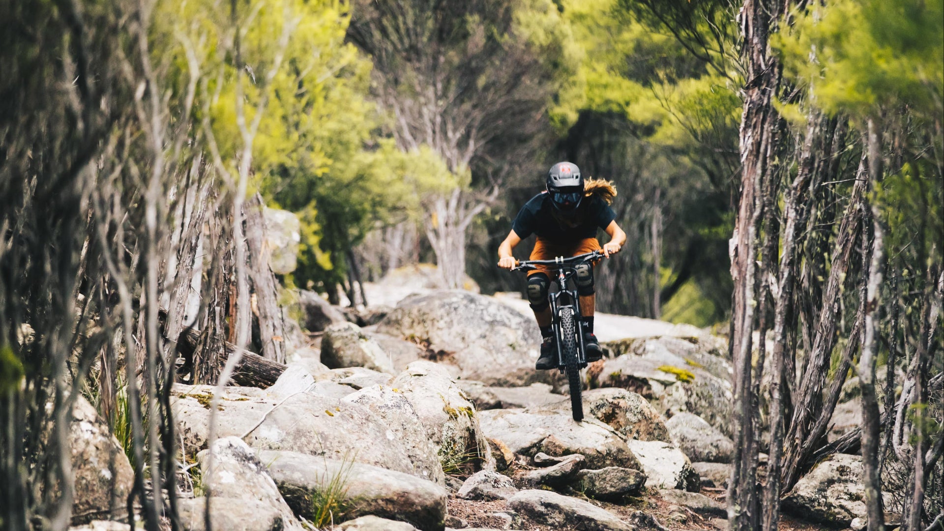 Person mountain biking on a rocky trail surrounded by trees in Derby Tasmania